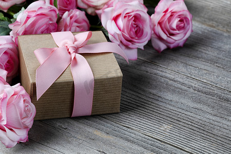 玫瑰礼盒摄影照片_母亲节爱情假期风化木板上背景粉红玫瑰礼盒的特写