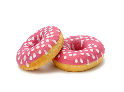 白色背景中带有粉红色糖衣和白色圆点的烤圆甜甜圈