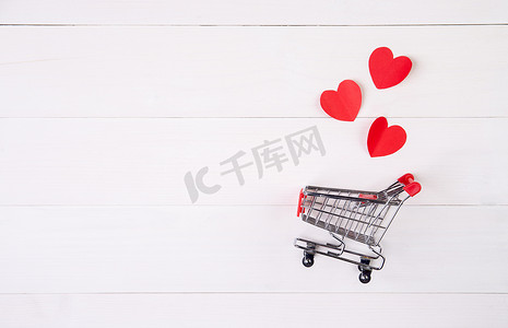 木桌上的购物车和心形纸，2 月 14 日情人节的销售概念，超市和商店，符号和庆祝活动，商业和假日销售概念。