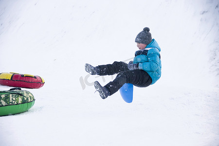 白俄罗斯，戈梅利市，2018 年 1 月 7 日。中央公园。从雪滑梯上拉雪橇。一个男孩从跳板上跳下雪橇。