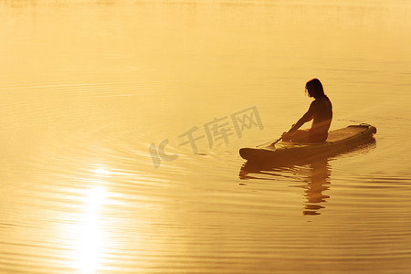 剪影的年轻男性桨手在 sup 板上放松
