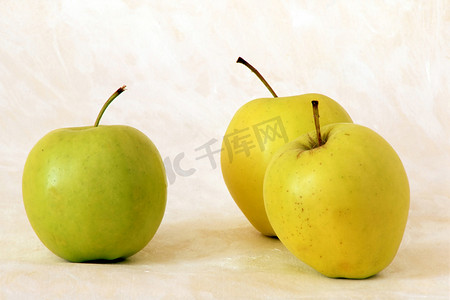 背景彩绘摄影照片_彩绘背景上的三个黄色苹果