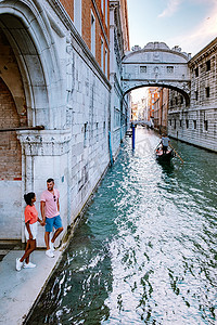 一对男女在意大利威尼斯的城市之旅中，色彩缤纷的街道上有运河威尼斯
