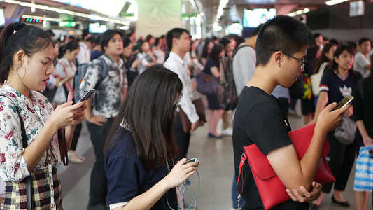 2018网络摄影照片_泰国曼谷-2018 年 12 月 18 日：泰国曼谷 BTS 轻轨站的乘客，每个人在等待 BTS 轻轨时都低头看着智能手机
