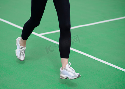 女运动员赛跑者脚在绿色跑道上奔跑。