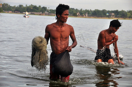 缅甸曼德勒 — 2015 年 11 月 21 日成年少数民族男子在水中行走时用网捕鱼，缅甸。