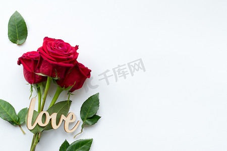 红玫瑰花束和白色背景上的装饰木字爱的组成。
