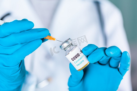 戴手套的护士摄影照片_女医生或护士穿着制服和戴面罩的手套在实验室拿着带有 COVID-19 冠状病毒疫苗标签的药瓶疫苗瓶