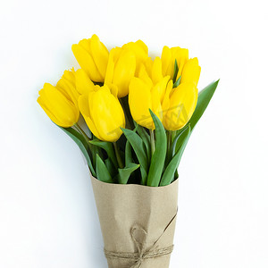 在白色背景上用牛皮纸包裹的黄色郁金香花束。