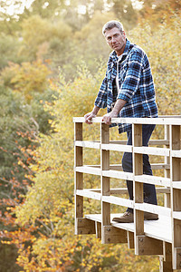男人站在木制阳台上俯瞰秋天的林地