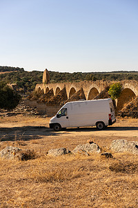 葡萄牙阿连特茹风景中的露营车，后面是废弃的被毁坏的 Ajuda 桥