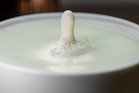 牛奶滴落入装满的杯子中。