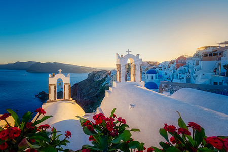 希腊圣托里尼岛日落时带蓝色圆顶和粉刷房屋的伊亚村圣托里尼岛