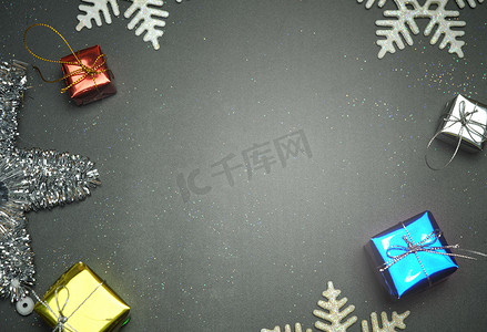 名片设计金色摄影照片_优雅的圣诞背景复制空间，金色雪花和铃铛，闪亮的礼盒，黑色木质背景。