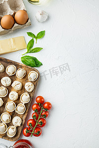 意大利饺子，木托盘中有新鲜的乳清干酪叶和西红柿，白色背景，顶视图平躺，有复制空间和文本空间