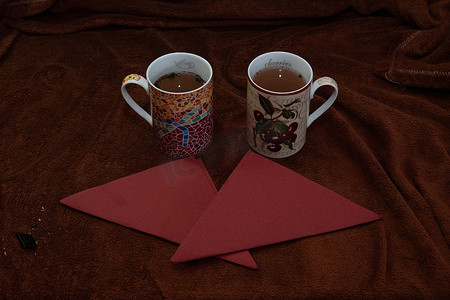 两杯茶和几张红色餐巾纸，上面是棕色黄油