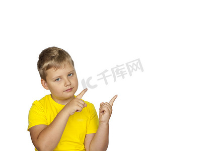 什么摄影照片_一个身穿黄色 T 恤、白色背景的男孩用手指指着什么。