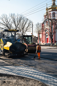 KYIV, UKRAINE - September 10, 2020：带有重型振动压路机的重型沥青压路机在街道上的道路施工现场压上新的热沥青和沥青摊铺机。