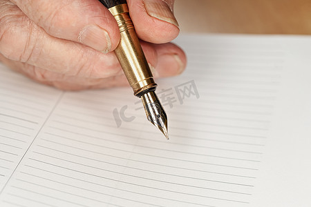 高级女性手中的金色钢笔即将在空白的日常计划页面上写点东西，特写细节