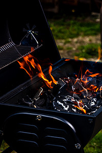 红色火焰摄影照片_带有红色火焰、热木炭煤球和余烬的炽热明火的烧烤坑