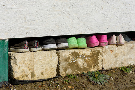 在花园的房子下面有一排各式各样的鞋子