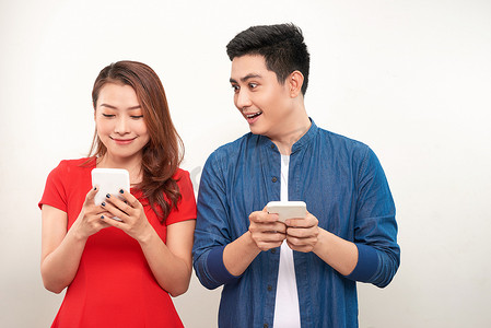亚洲夫妇使用小工具：漂亮女孩在手机上打字，而她的男朋友站在她旁边，低头看着她的智能手机屏幕