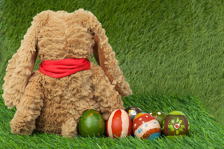 复活节耶稣摄影照片_兔子，坐在绿草上，后面是一群彩蛋