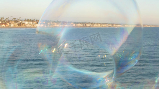 在加利福尼亚州的海洋码头上吹肥皂泡，夏季背景模糊。