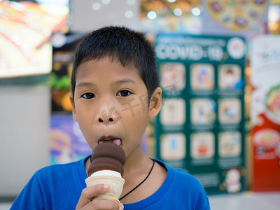 商城美摄影照片_一个男孩在背景模糊的商场里吃冰淇淋。