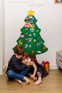 两个孩子在圣诞树前的地板上拥抱