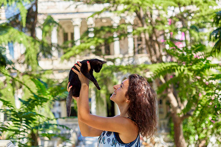 一个小女孩和她在街上捡到的一只黑猫玩耍