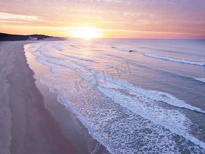 日出在海洋和空荡荡的海滩上的航拍
