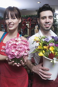 花店站着，手里拿着一桶切花和一朵绣球花