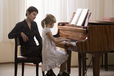 女孩（5-6岁）在老师的伴奏下弹奏钢琴