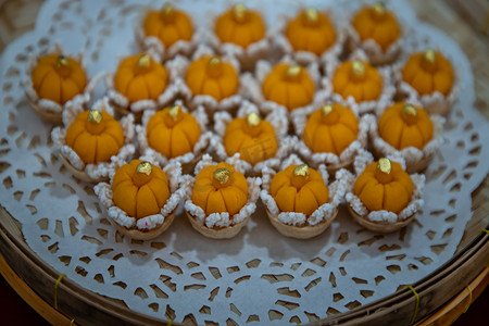 吉祥麒麟摄影照片_优雅美丽的泰式甜点 (Khanom Wan Thai) 在手工制作的竹篮中供应，金色和不同花朵形状的叮咬。泰式甜点，吉祥甜点。