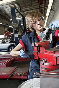 防护汽车摄影照片_身着防护服的年轻技工专注于维修车库中的机械零件
