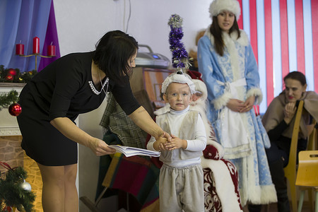 12狂欢节摄影照片_白俄罗斯，Gomil 市，2018 年 12 月 27 日。幼儿园的晨会。在幼儿园的圣诞日场上穿着狂欢节服装的滑稽男孩。