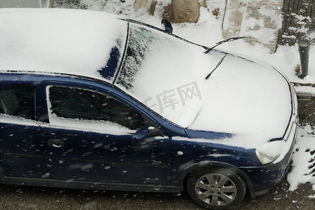 汽车扬起的沙摄影照片_希腊塞萨洛尼基在被雪覆盖的汽车前抬起雨刷器。