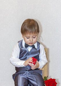 一个小男孩拿着一个红色的盒子，递过来，这是情人节的主题概念。