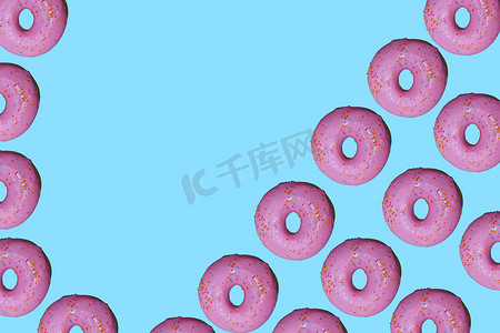 甜甜圈图案摄影照片_甜甜圈图案平放在顶视图蓝色背景上。