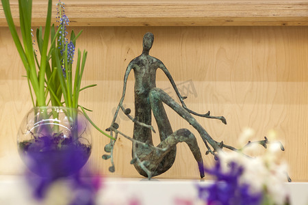一个象征自然的金属雕像矗立在木架子上。