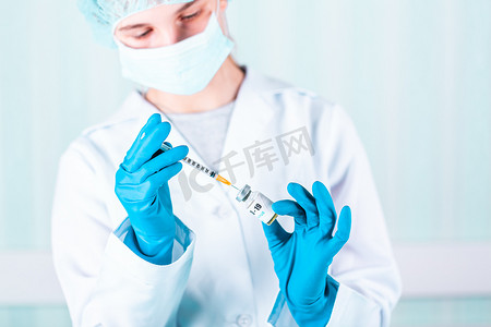 女医生或护士穿着制服和戴面罩的手套在实验室拿着带有 COVID-19 冠状病毒疫苗标签的药瓶疫苗瓶