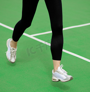 女运动员赛跑者脚在绿色跑道上奔跑。