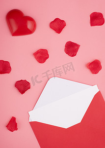 粉红色背景中带空白、心形和玫瑰花瓣的打开信封