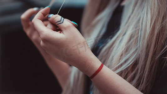 手指的箭头摄影照片_手指上有箭头的女性手，手腕上有红线-纹身。