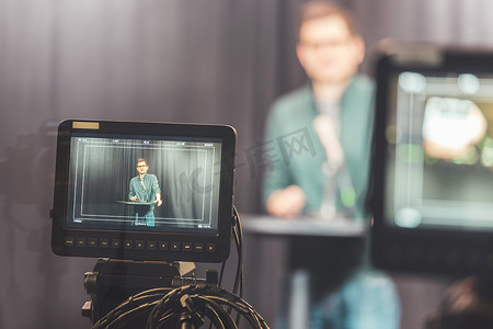 电视录音室的年轻记者正在对着麦克风和模糊的胶卷相机讲话