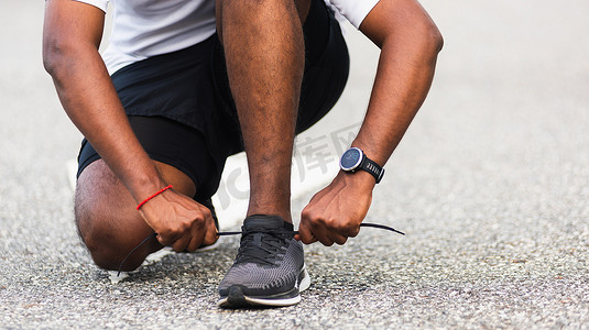 运动赛跑者黑人戴手表坐着他试着系着鞋带跑