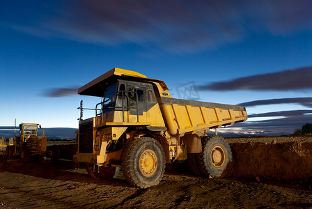 矿用挖掘机摄影照片_巨大的自动倾卸黄色矿用卡车夜间射击和挖掘机