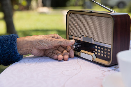 在后院老式收音机上的高级女人手转动旋钮。