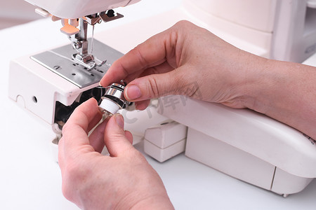 裁缝将梭芯放在缝纫机的梭芯盖中。